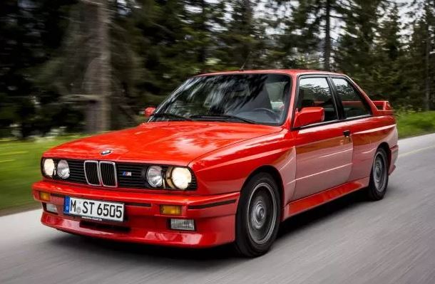 BMW M3 E30 rouge roulante, vue avant gauche avec élargisseurs d’ailes