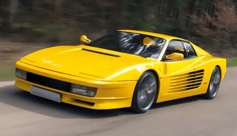 Ferrari Testarossa jaune en mouvement vue de face trois quarts avec entrées d’air latérales sur route