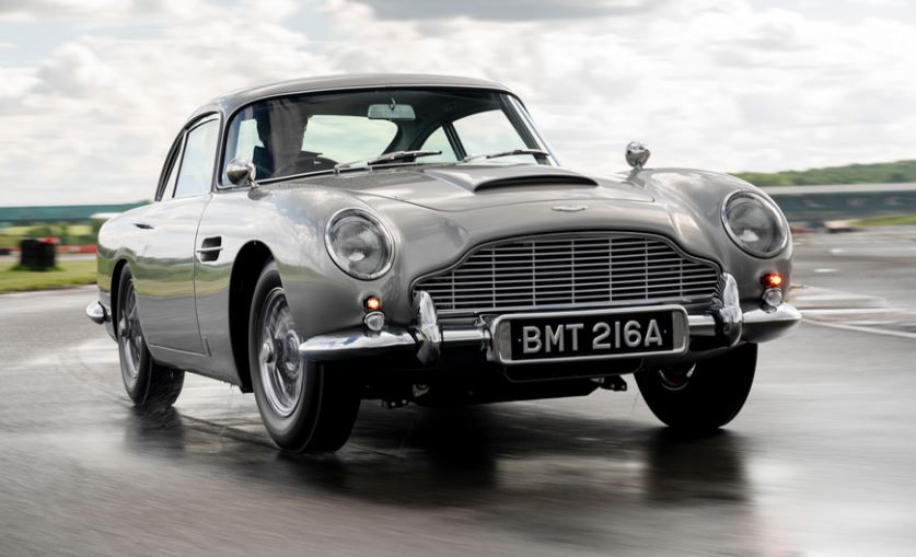 Aston Martin DB5 argent vue avant droite sur circuit humide