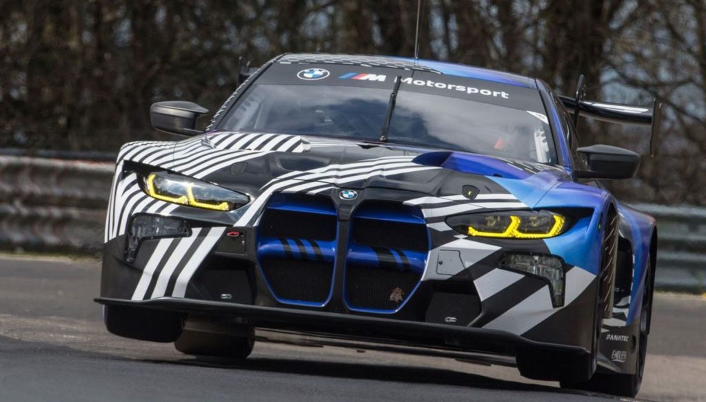 BMW M4 GT3 camouflage noir et bleu vue de face avec phares jaunes