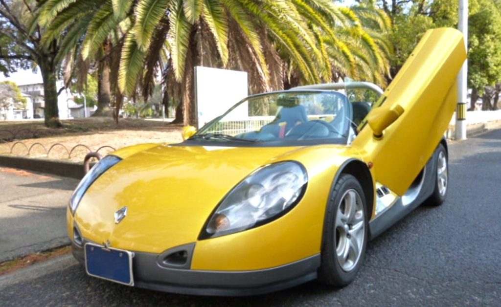 Renault Spider jaune avec porte ouverte, roadster radical exposé dans une rue japonaise