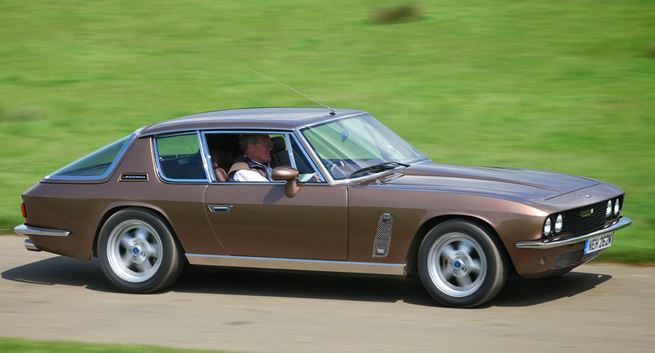 Jensen Interceptor marron en roulage sur route de campagne, silhouette élégante de GT britannique