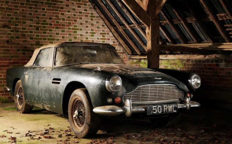 voiture ancienne Aston Martin DB4 cabriolet abandonnée dans une grange poussiéreuse sortie de grange