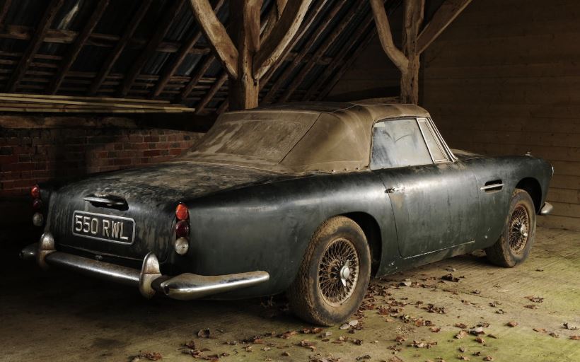 Aston Martin DB4 cabriolet poussiéreuse vue arrière dans une grange en bois