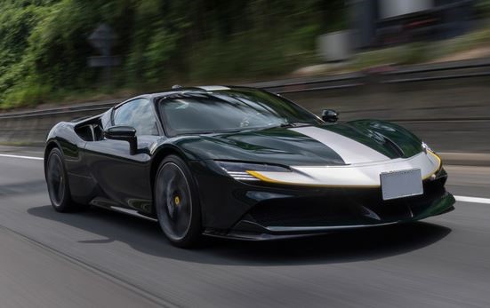 Ferrari SF90 Stradale verte en mouvement vue de face trois quarts avec bande blanche sur route