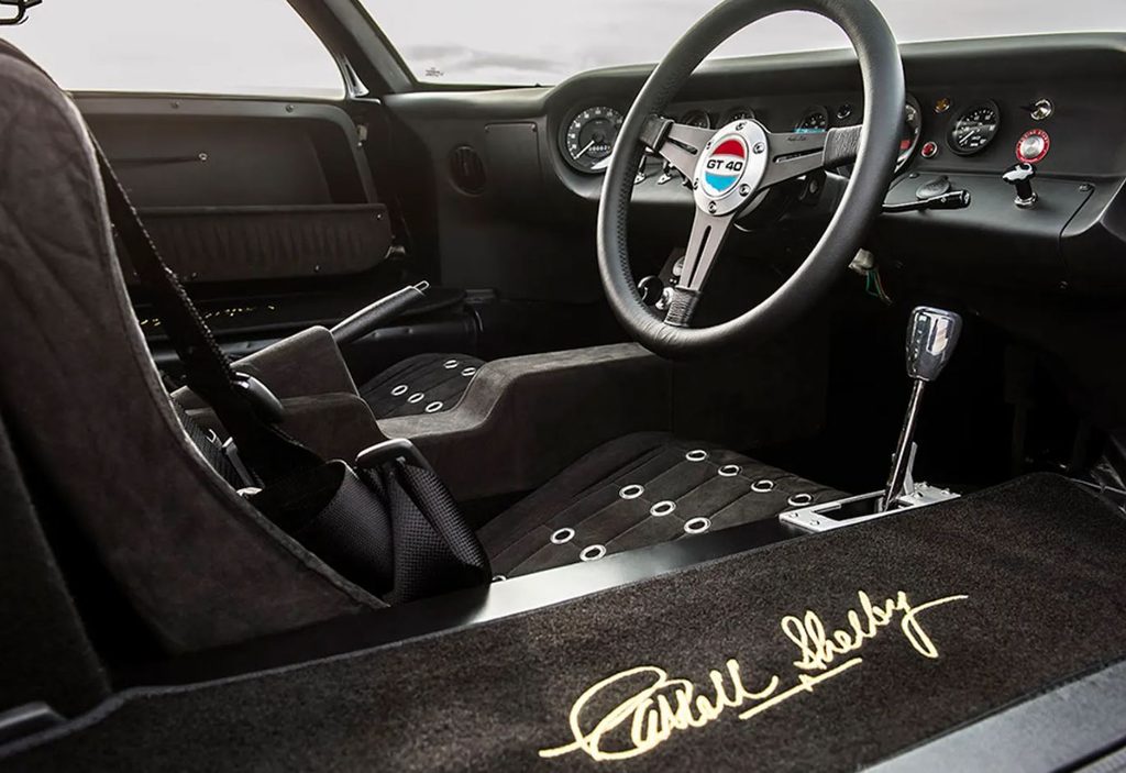 Habitacle de Ford GT40 avec volant à trois branches, instrumentation de course et sièges baquets noirs.