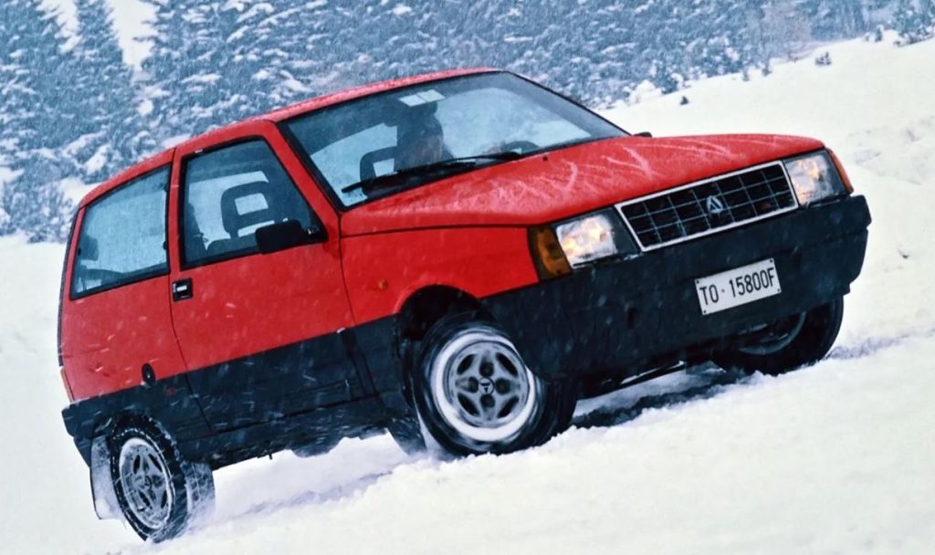 Autobianchi Y10 4WD rouge sur route enneigée, symbole des dernières années de la marque