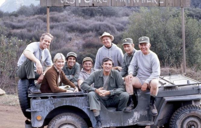 Équipe médicale du film M.A.S.H posant sur une Jeep militaire américaine