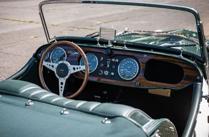 Tableau de bord en bois et volant trois branches dans l’habitacle d’une Morgan Plus 4 ancienne