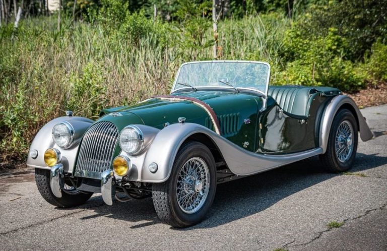 Morgan Plus 4 bicolore vert et aluminium vue avant gauche sur route dégagée