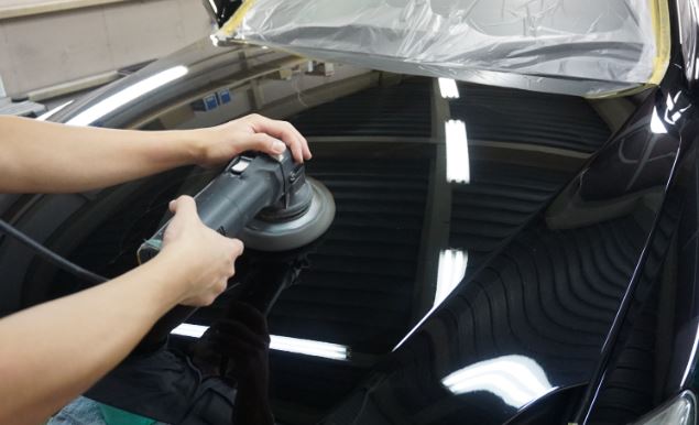 Application d’un polish voiture à la polisseuse orbitale sur carrosserie noire
