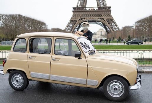 Renault 4L beige stationnée devant la tour Eiffel à Paris, symbole de la voiture populaire française