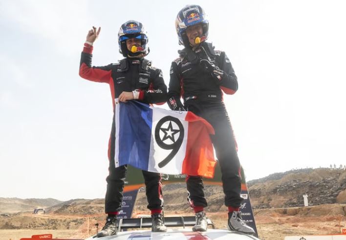 Sébastien Ogier célébrant son neuvième titre mondial WRC avec son copilote en 2025.
