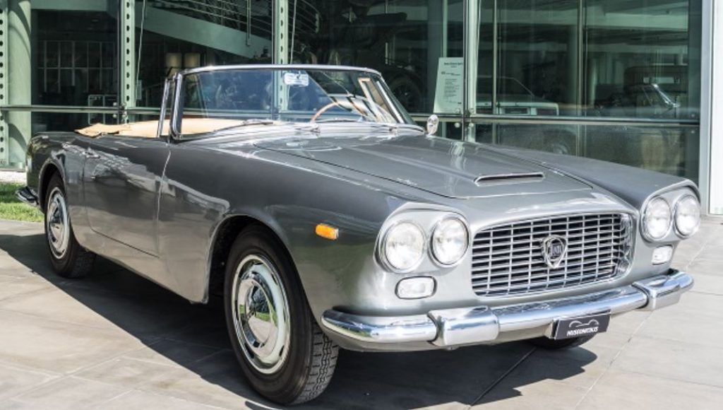 Lancia Flaminia Touring cabriolet grise stationnée devant un bâtiment moderne