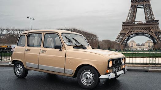 Renault 4 beige stationnée à Paris avec la tour Eiffel en arrière-plan