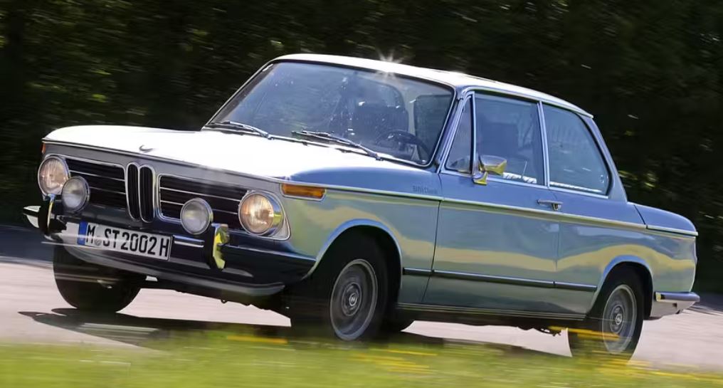 BMW 2002 tii grise roulant sur route, berline sportive allemande des années 70