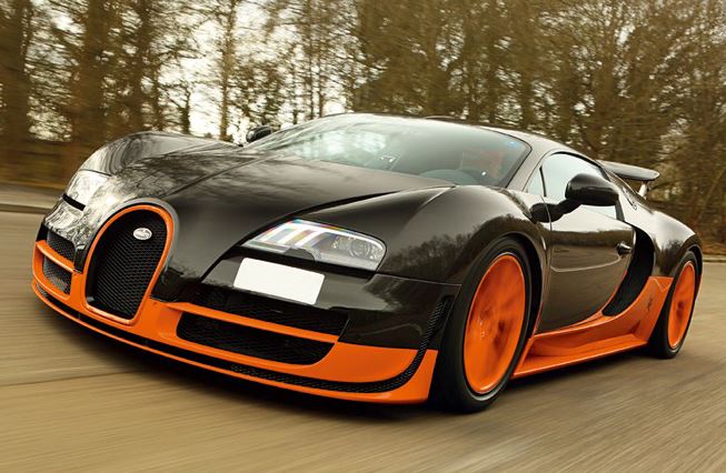 Bugatti Veyron noire et orange en mouvement vue de face trois quarts sur route avec design de supercar