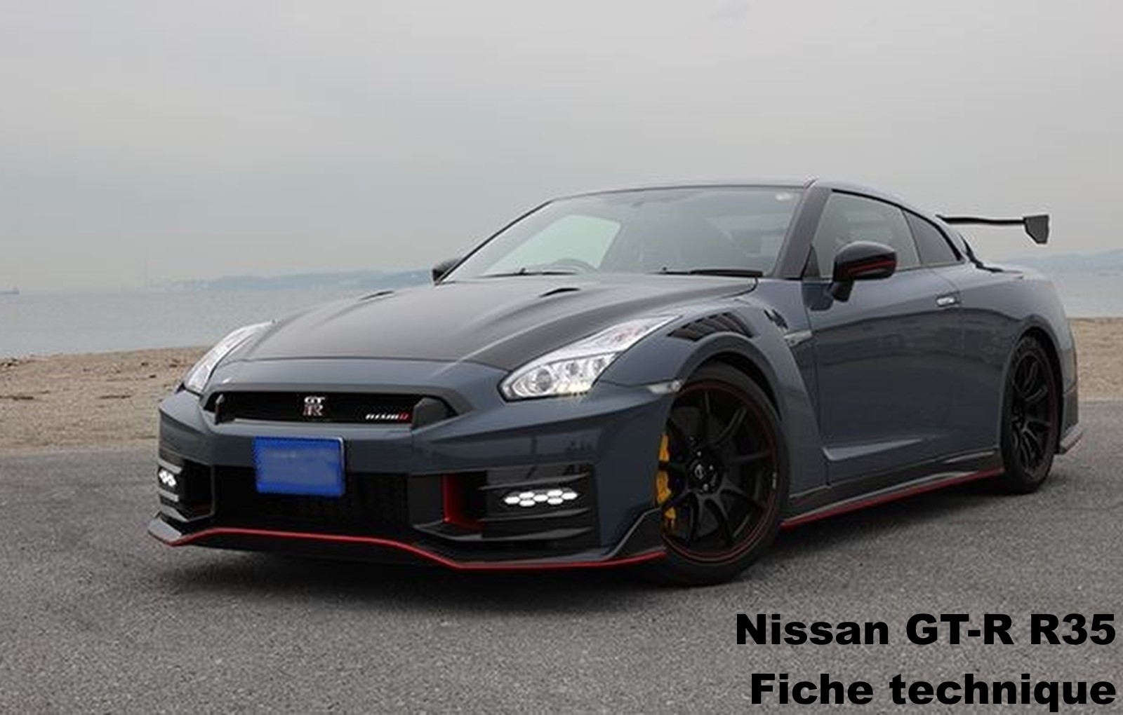 Nissan GT-R R35 Nismo gris vue trois quarts avant sur route en bord de mer
