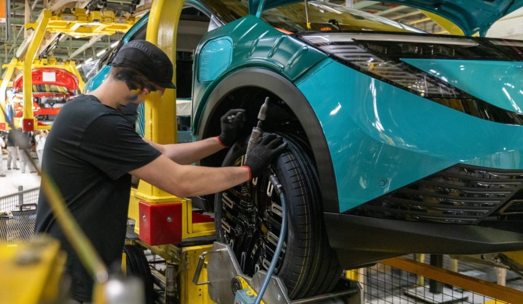 Opérateur installant une roue sur un véhicule en cours d’assemblage dans une usine automobile britannique