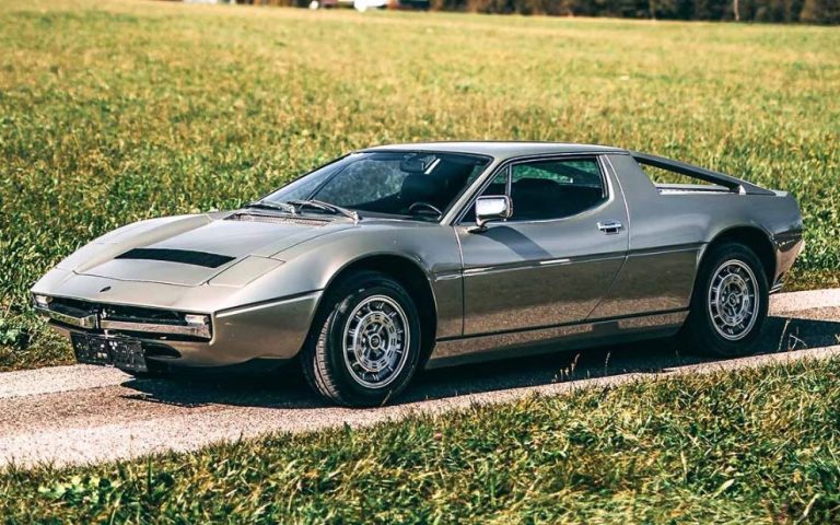 Maserati Merak grise stationnée sur une petite route de campagne, vue trois-quarts avant