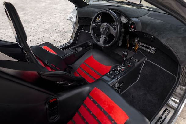 Intérieur de la McLaren F1 avec poste de conduite central et sièges sport rouges