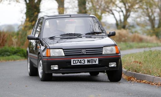 Peugeot 205 GTI noire en roulage sur route, vue avant