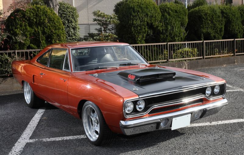 Plymouth Road Runner orange stationnée, version modifiée avec capot noir et jantes larges
