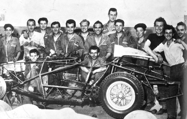 Équipe de l’atelier Scaglietti posant autour d’un châssis Ferrari en cours de construction.