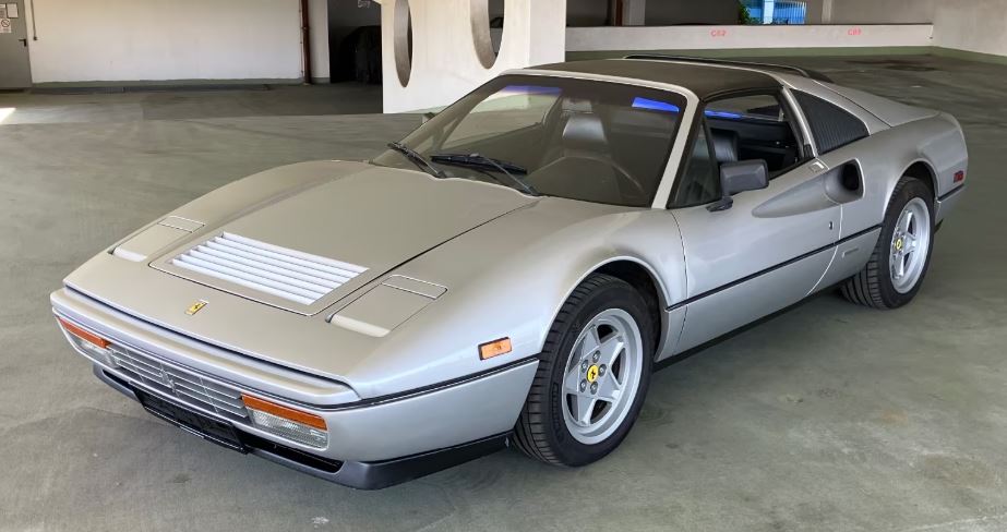 Ferrari 328 GTS 1986 grise stationnée dans un parking en bon état apparent