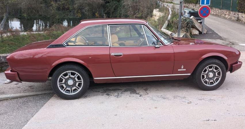 Peugeot 504 Coupé V6 injection 1980, vue de profil, carrosserie bordeaux en bon état