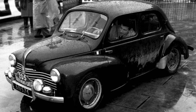 Renault 4CV photographiée sous la pluie, vue de trois-quarts avant en noir et blanc