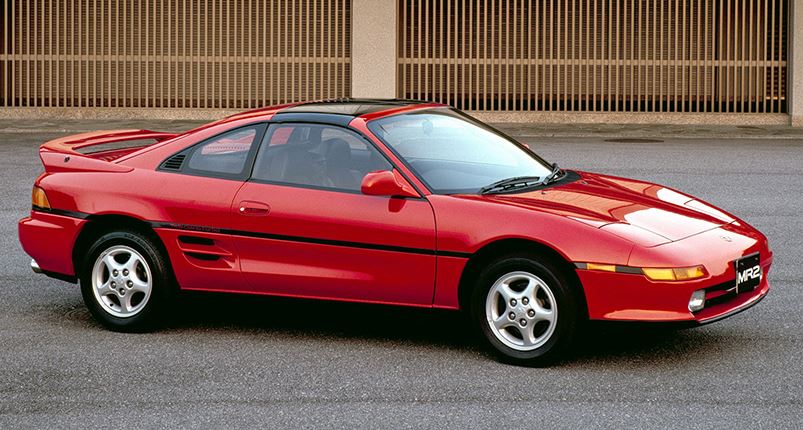 Toyota MR2 rouge des années 1990, vue de profil en milieu urbain