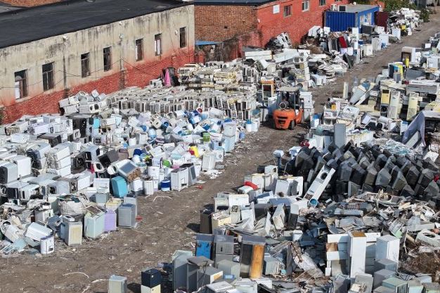 Décharge remplie d’appareils électroménagers usagés et abandonnés, illustrant la société du jetable et le remplacement plutôt que la réparation.
