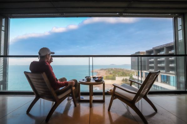 Personne assise face à la mer sans activité apparente sur une terrasse