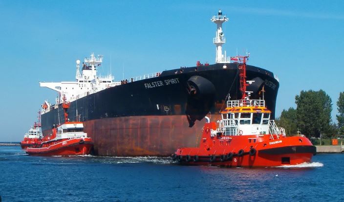 Pétrolier transportant du pétrole brut escorté par des remorqueurs dans un port