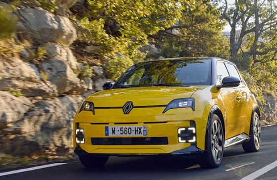 Renault 5 électrique jaune roulant sur une route de montagne