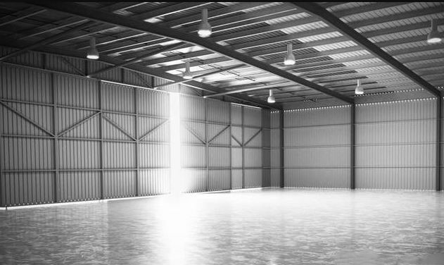 Entrepôt logistique vide avec structure métallique et éclairage industriel, illustrant la baisse d’activité liée à la taxe sur les petits colis en France.