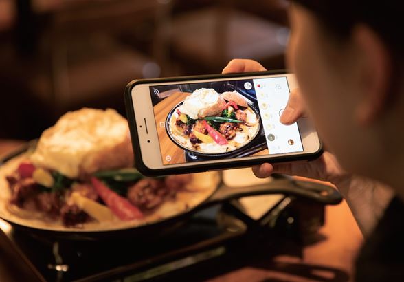 Personne photographiant son plat au restaurant avec un smartphone