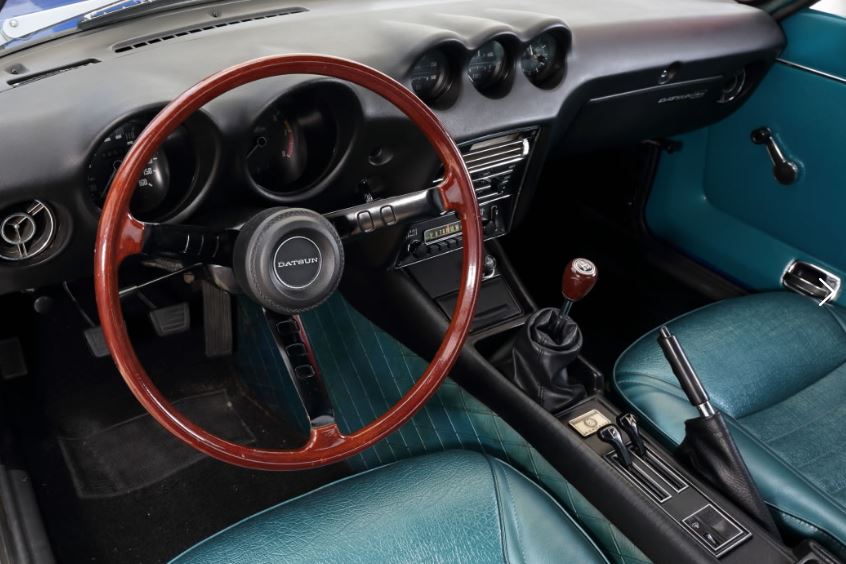habitacle d’une Datsun 240Z avec volant bois et trois compteurs centraux sur la planche de bord