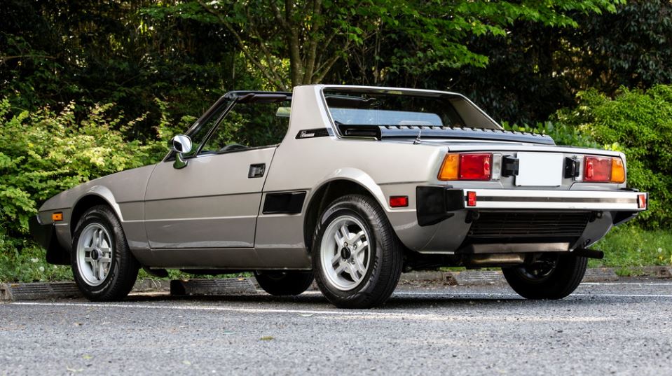 Fiat X1/9 beige vue trois quarts arrière, silhouette anguleuse typique des années 1970