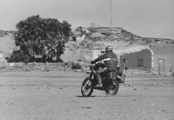 moto engagée dans le rallye Abidjan-Nice traversant un village saharien en 1977
