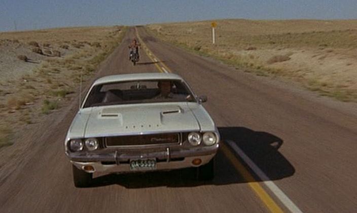 Dodge Challenger blanche roulant sur une route désertique dans le film Point Limite Zero (1971)