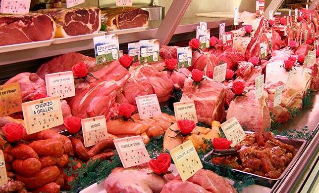 Étal de boucherie avec viandes et étiquettes de prix visibles