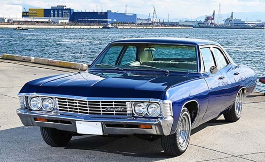 Chevrolet Impala 1965 berline américaine full size garée en bord de mer, style typique des voitures US