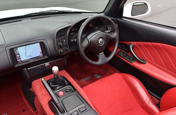 intérieur Honda S2000 avec sièges rouges, cockpit orienté conducteur et boîte manuelle