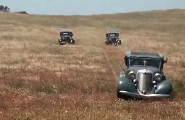 Voitures poursuivant une Ford V8 dans les champs pendant la cavale de Bonnie and Clyde