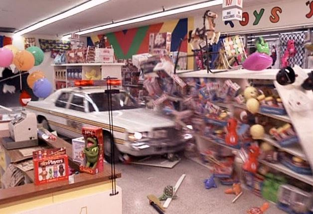 Voiture de police traversant un magasin dans une scène culte de Blues Brothers