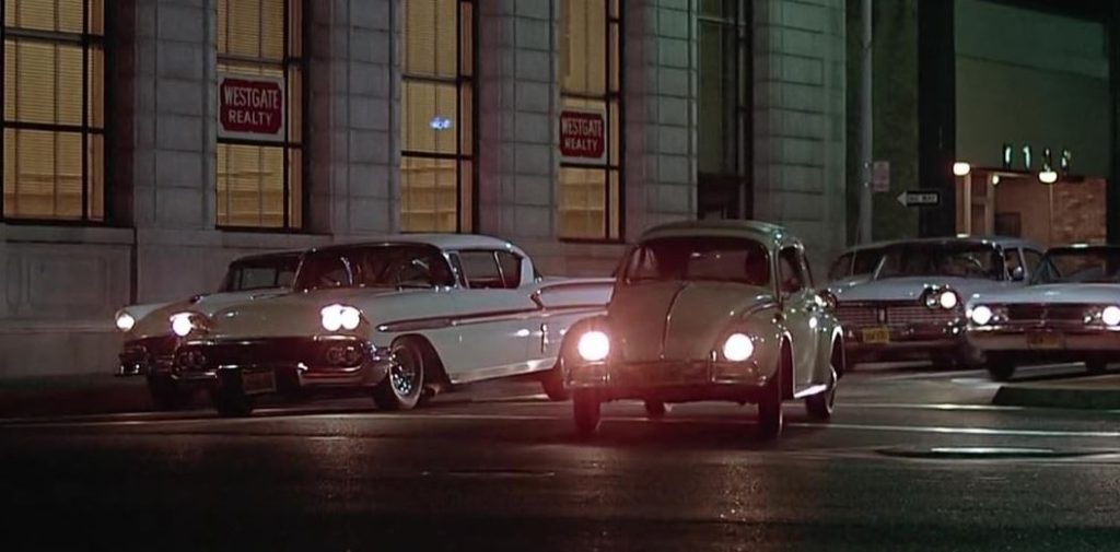 Volkswagen Coccinelle entourée de voitures américaines American Graffiti