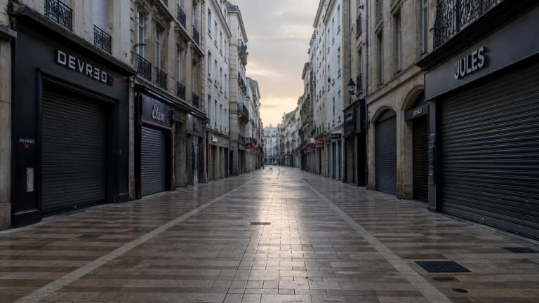 Rue piétonne de centre-ville avec commerces fermés et rideaux baissés