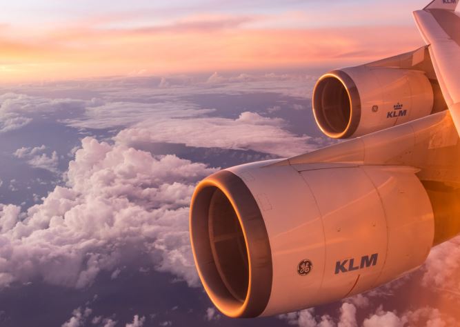 Réacteur d’avion de ligne au-dessus des nuages illustrant le contraste entre écologie punitive et transport aérien international.